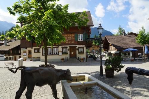 a statue of a cow standing next to a fountain at Posthotel Rössli in Gstaad