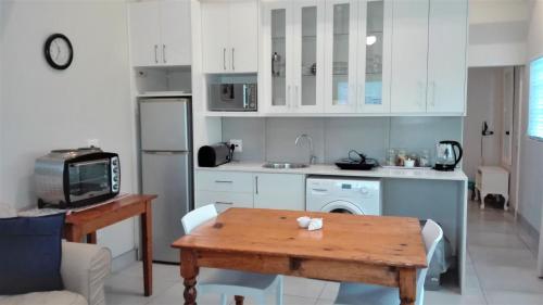uma cozinha com armários brancos e uma mesa de madeira em Seashell Cottage em Hermanus