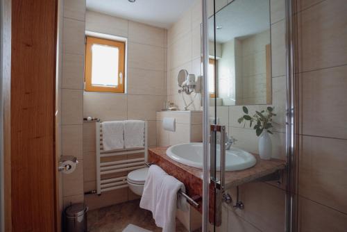a bathroom with a sink and a toilet and a mirror at Beim Kathrein - inklusive SILVRETTA Card Premium in Galtür