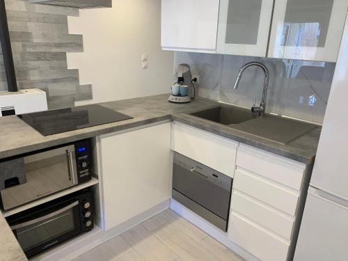 a white kitchen with a sink and a microwave at Appartement cocooning pour un séjours à Tende in Tende