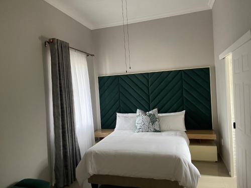 um quarto com uma cama grande e uma cabeceira verde em Casa da Flores Port Edward RSA em Port Edward