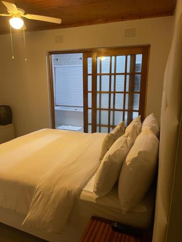 a bedroom with a bed with white pillows and a window at Casa da Flores Port Edward RSA in Port Edward
