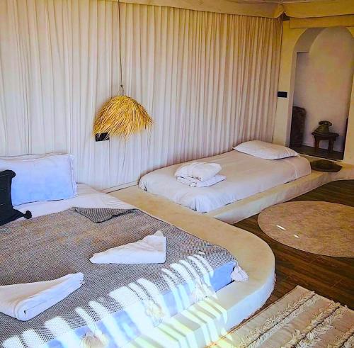 a room with two beds and a table with towels at Agafay Luxury camp in Marrakech