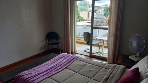 een slaapkamer met een bed en een raam met een ventilator bij Hospedaria Rofamos in Conselheiro Lafaiete