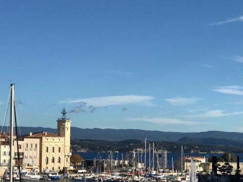 a building with a clock tower and boats in a harbor at Accostage Vieux-Port - Appartements & Parking en option in La Ciotat