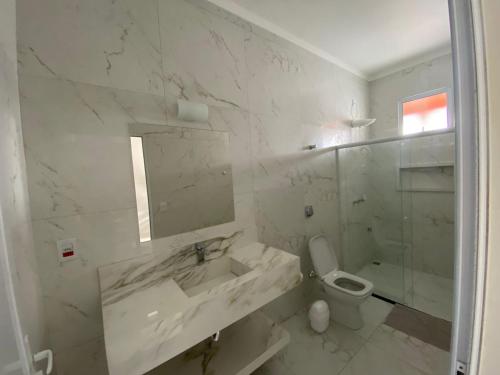 ein weißes Bad mit einem Waschbecken und einem WC in der Unterkunft Casa De Temporada Eldorado 2 in Olímpia
