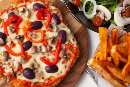 a pizza with peppers and mushrooms next to a plate of fries at Radisson RED Miraflores in Lima