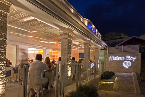 a group of people sitting at a restaurant at night at Melina Bay Boutique Hotel in Kassiopi