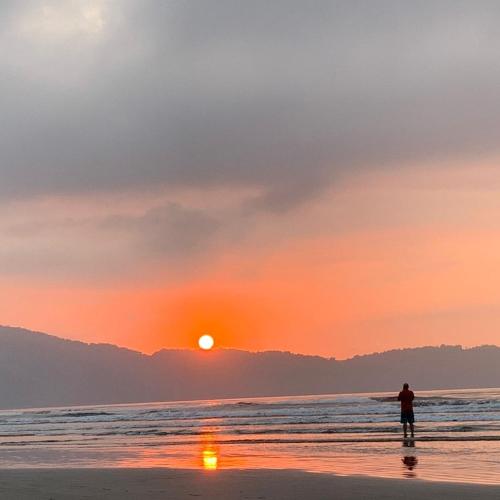 a man standing on the beach watching the sunset at Mayda hostel in Praia Grande