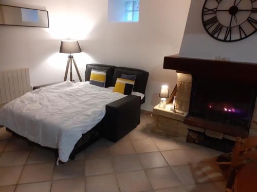 a bedroom with a bed and a fireplace with a clock at DANS LA MAISON D'A COTE in Azerables
