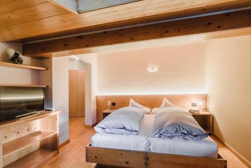 a bedroom with a bed and a flat screen tv at Cesa Edelweiss Living & Spa in Campitello di Fassa