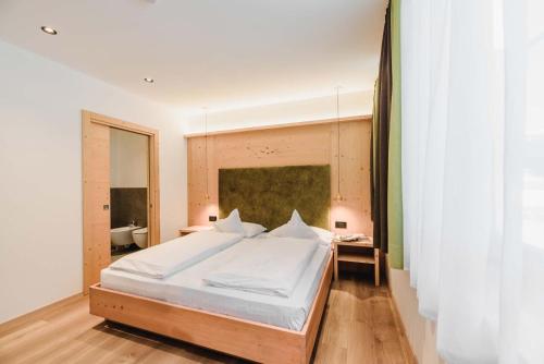 a bedroom with a large white bed and a bathroom at Cesa Edelweiss Living & Spa in Campitello di Fassa