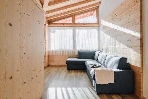 a living room with a blue couch and a window at Cesa Edelweiss Living & Spa in Campitello di Fassa