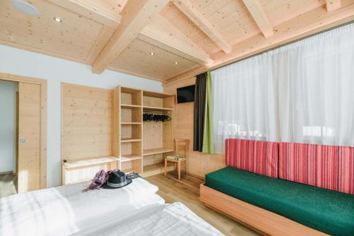 a bedroom with two beds and a red and green couch at Cesa Edelweiss Living & Spa in Campitello di Fassa