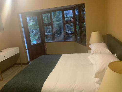 a bedroom with a large white bed and a window at Marina Views Guesthouse in Hartbeespoort