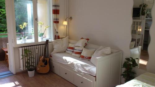 eine weiße Couch in einem Zimmer mit Gitarre in der Unterkunft Green Oasis in Berlin