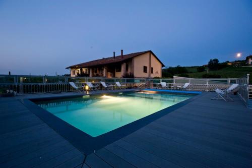 a swimming pool with chairs and a house at Amalia Cascina in Langa in Monforte dʼAlba