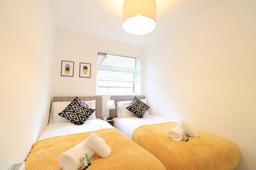 2 camas individuais num quarto com paredes brancas em Detached Bungalow - Sleeps 8 - Free Parking, Fast Wifi, Smart TV and Garden by Yoko Property em Northampton