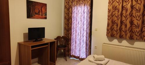 a room with a bed and a television on a table at Anilio Rooms in Anilio Metsovo