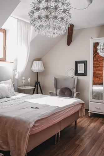 a bedroom with a large bed and a chandelier at Penzion Adamův Dvůr in Masákova Lhota
