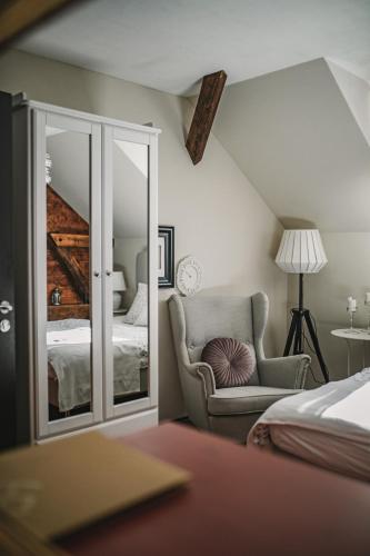 a bedroom with a bed and a chair and a mirror at Penzion Adamův Dvůr in Masákova Lhota