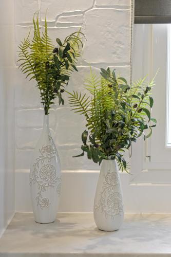 two white vases with plants in them on a table at Sea & Olives Suites Hotel and Villas in Plaka