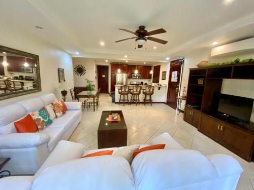 a living room with white couches and a flat screen tv at Monte Carlo Luxury Condominiums in Jacó