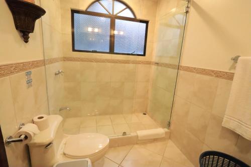 a bathroom with a toilet and a glass shower at Monte Carlo Luxury Condominiums in Jacó