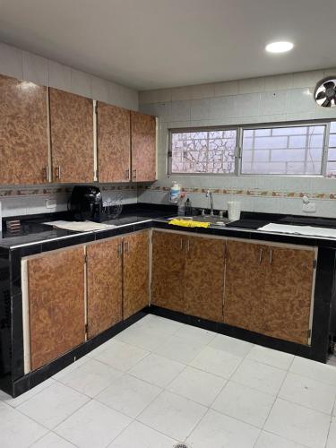 a kitchen with wooden cabinets and black counter tops at MonDieu Hostel in Barranquilla