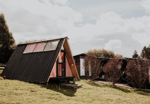 a small house with a black roof on a field at Mini Chalet de lujo en Guatavita in Guatavita