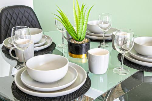 a glass table with plates and glasses and a plant at Penthouse Apartment - City Centre - Free Parking, Balcony, Fast Wifi and Smart TV with Netflix by Yoko Property in Milton Keynes