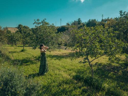 a woman standing in a field with trees at Relais Terre di Romanello in Noto
