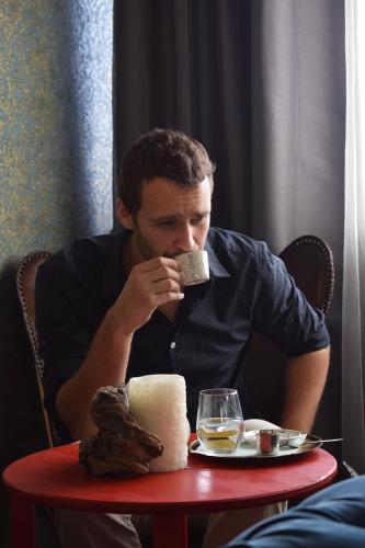 a man sitting at a table drinking from a cell phone at Penzion Adamův Dvůr in Masákova Lhota