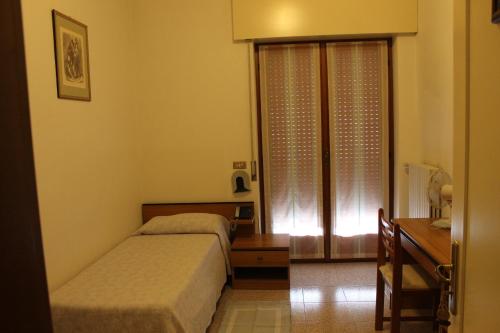 a bedroom with two beds and a desk and a window at Hotel O'Scugnizzo 2 in Belluno