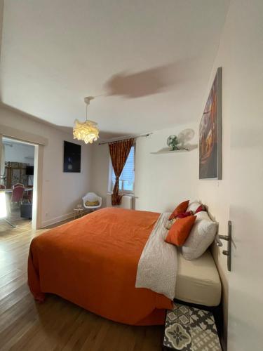 a bedroom with a bed with an orange bedspread at Le Cosy in Schiltigheim