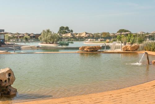 a pool of water in a park with a fountain at Terme di Vulci Glamping & Spa in Canino