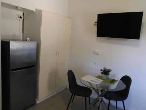 a room with a table and a refrigerator and a table and chairs at Caravilla Motor Inn in Taree