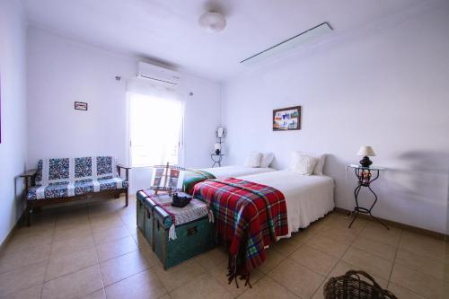 a white bedroom with a bed and a chair at Os 5 Sentidos in Mourão