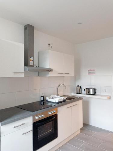 a kitchen with white cabinets and a black oven at Modern & cozy Rooms Leipzig-Gohlis in Leipzig