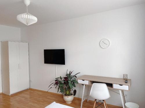 a white room with a desk and a clock on a wall at Modern & cozy Rooms Leipzig-Gohlis in Leipzig