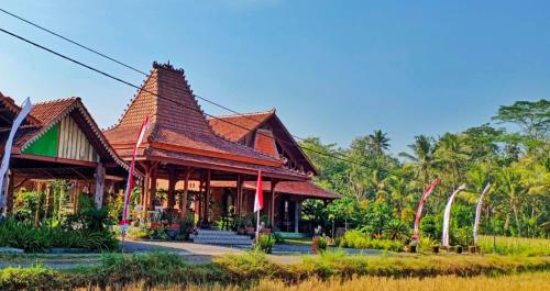 a building with a roof on top of a field at Bhumi Kasuryan Borobudur in Borobudur