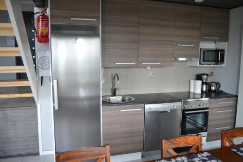 a kitchen with wooden cabinets and a stainless steel refrigerator at Riihilintu Villa in Muurame