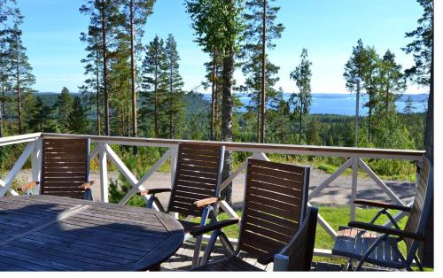 una mesa y sillas en una terraza con vistas a los árboles en Riihilintu Villa, en Muurame