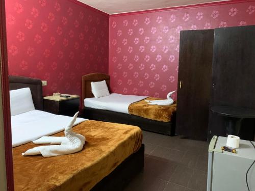 a room with two beds with pink walls at Kerotel Egypt in Cairo