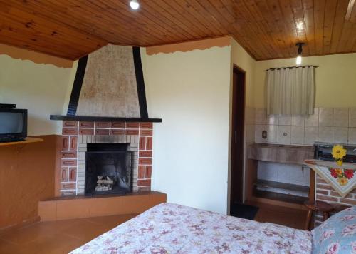 a bedroom with a brick fireplace and a bed at Pousada Borogan in Monte Verde