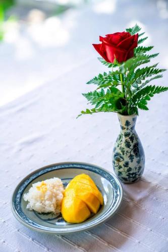 a plate of rice and a vase with a red rose at Amata Lanna Village อมตะล้านนาวิลเลจ in Chiang Mai