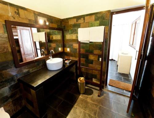 a bathroom with a sink and a mirror and a shower at Kanan Beach Resort in Nīleshwar