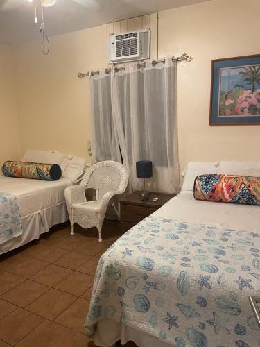 a bedroom with two beds and a chair and a window at Midtown Guest House in Charlotte Amalie