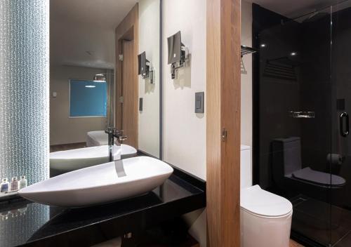 a bathroom with two sinks and a toilet and a shower at Hotel Real del Rio in Tijuana