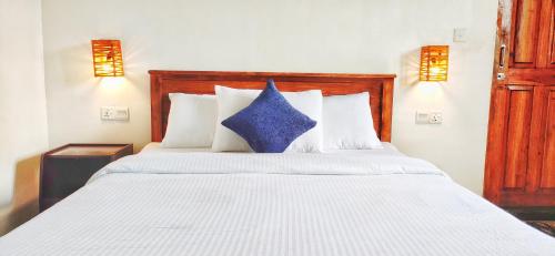 a bedroom with a white bed with a blue pillow at RC AWKWARD in Nuwara Eliya